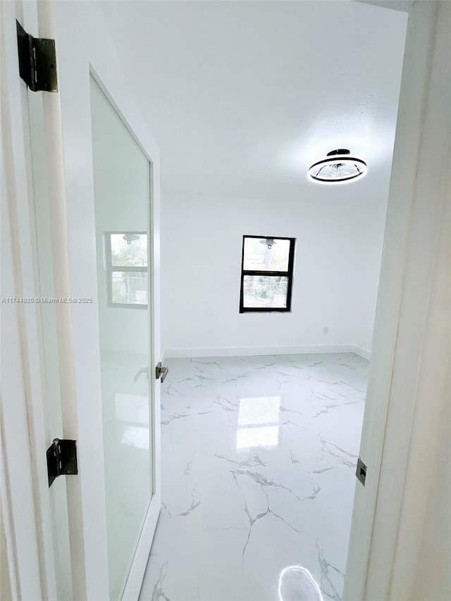 hall with marble finish floor, a wealth of natural light, and baseboards