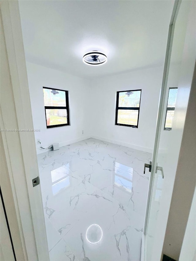 bathroom with marble finish floor, a healthy amount of sunlight, and baseboards