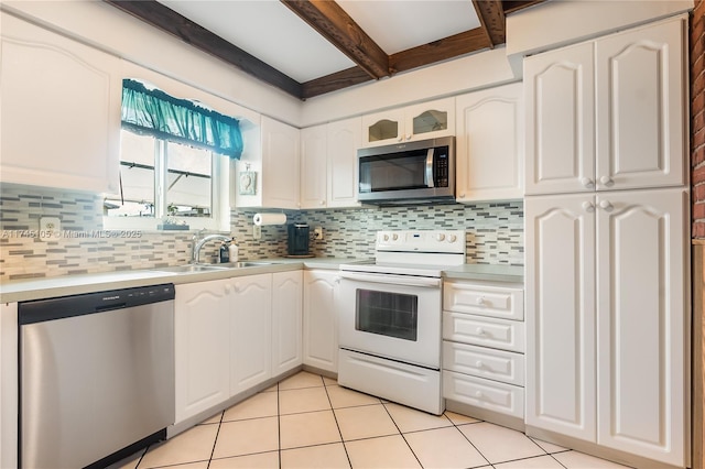 kitchen featuring appliances with stainless steel finishes, beamed ceiling, sink, white cabinets, and backsplash