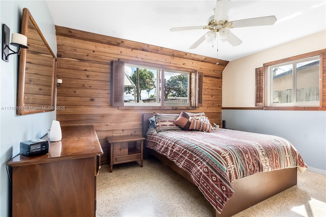 bedroom with multiple windows, wooden walls, and ceiling fan