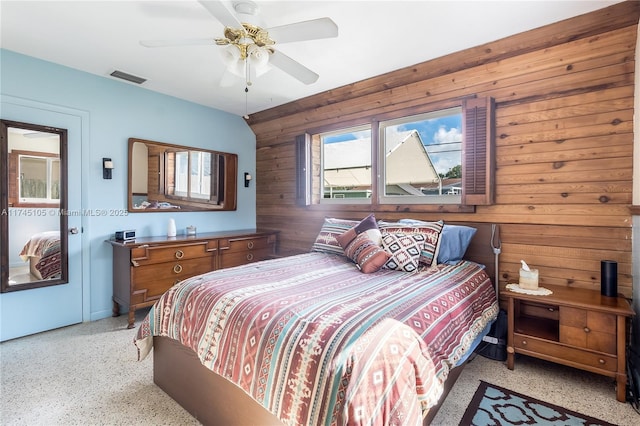 bedroom featuring ceiling fan and wood walls