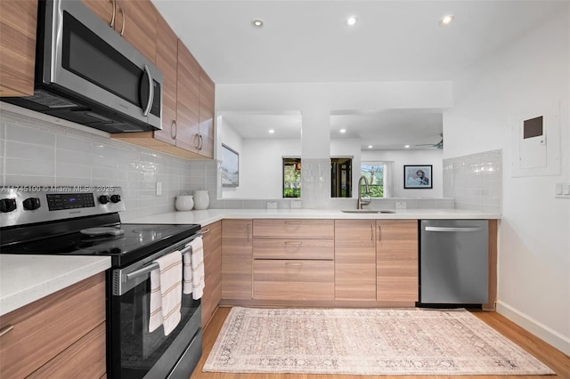 kitchen with stainless steel appliances, sink, light hardwood / wood-style flooring, and decorative backsplash