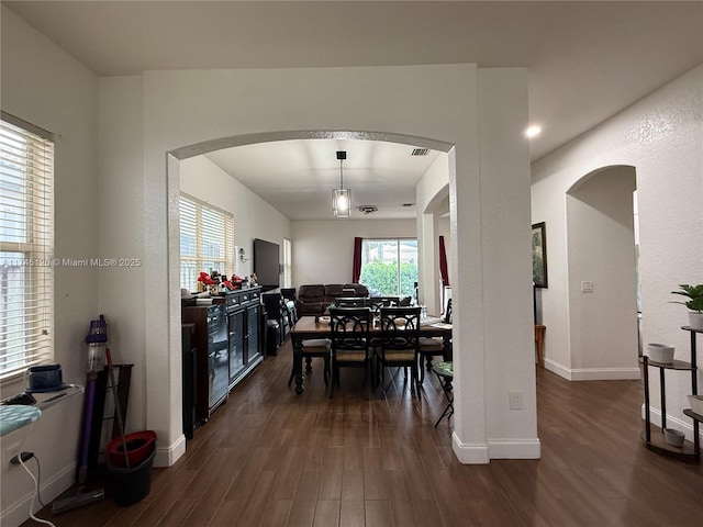 dining room featuring visible vents, baseboards, arched walkways, and dark wood-style flooring