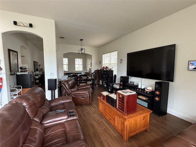 living room featuring arched walkways, baseboards, and wood finish floors