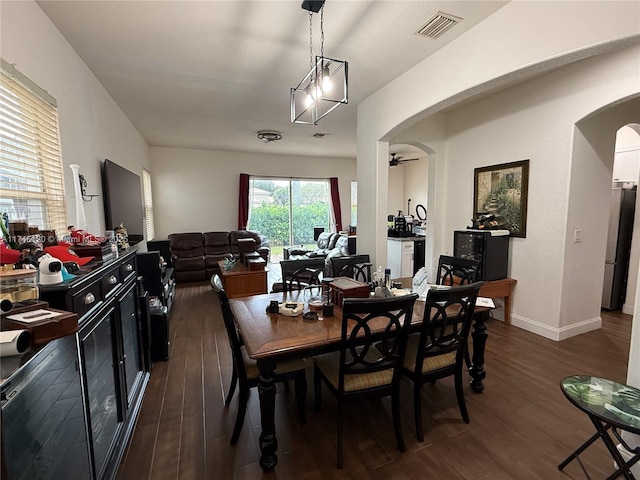 dining space featuring a ceiling fan, visible vents, baseboards, dark wood finished floors, and arched walkways