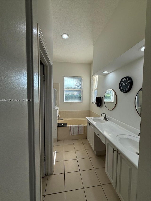 bathroom featuring a textured ceiling, a bath, tile patterned flooring, and a sink