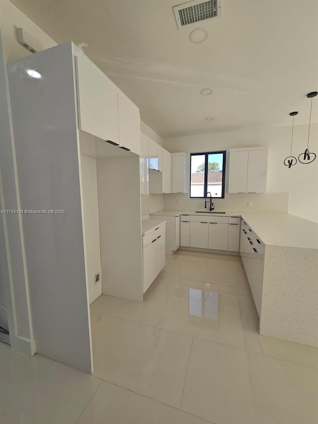 kitchen with pendant lighting, white cabinetry, sink, and light tile patterned floors