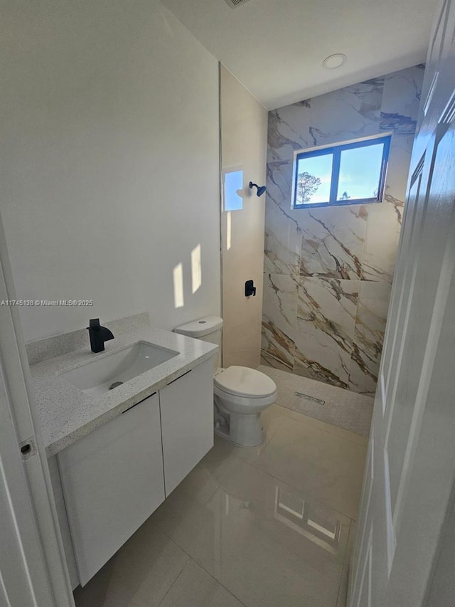 bathroom with vanity, a tile shower, and toilet