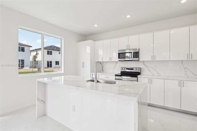 kitchen with stainless steel appliances, light stone countertops, sink, and white cabinets