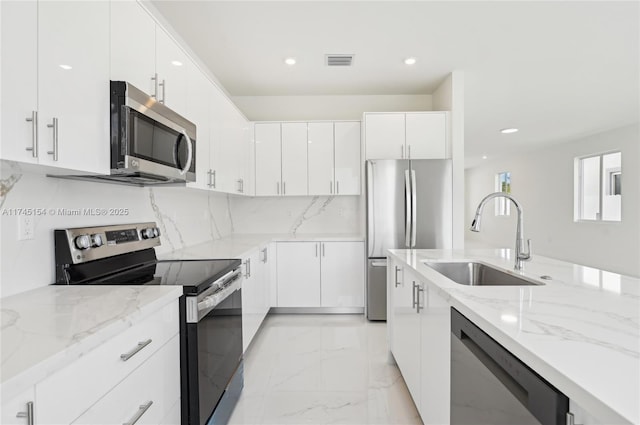 kitchen with sink, white cabinetry, appliances with stainless steel finishes, light stone countertops, and backsplash