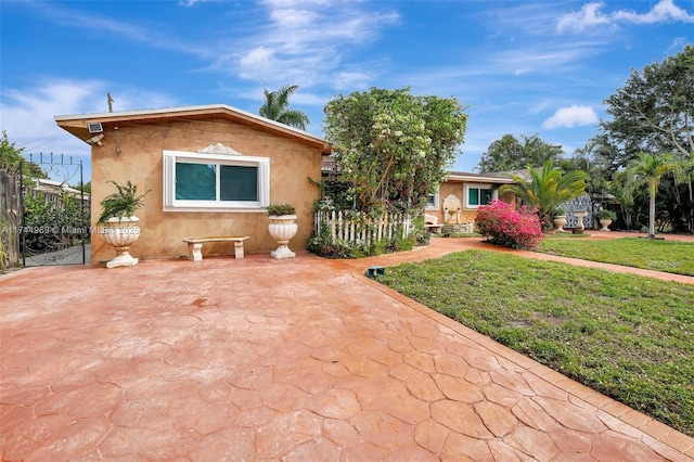 view of front of house featuring a front yard, fence, and stucco siding