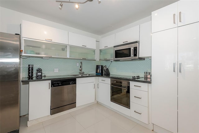 kitchen with light tile patterned flooring, appliances with stainless steel finishes, sink, white cabinets, and decorative backsplash