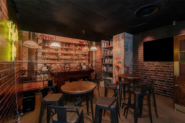 bar featuring pendant lighting, brick wall, and carpet