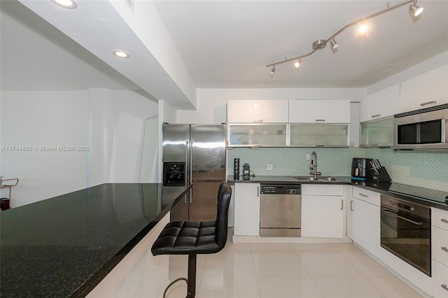 kitchen with sink, backsplash, white cabinets, and appliances with stainless steel finishes