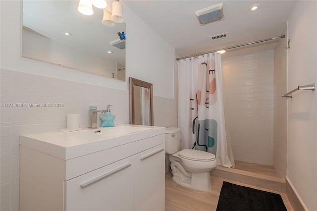 bathroom featuring hardwood / wood-style flooring, tile walls, vanity, curtained shower, and toilet