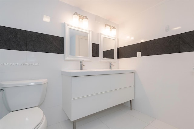 bathroom with tile patterned floors, vanity, toilet, and tile walls