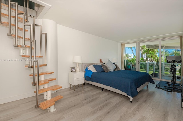 bedroom featuring access to outside, light hardwood / wood-style floors, and floor to ceiling windows