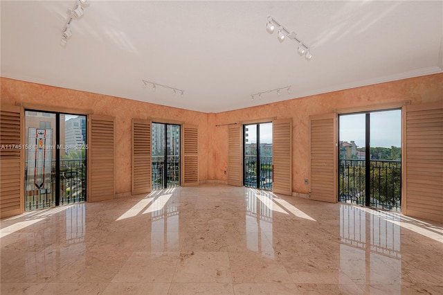 spare room featuring marble finish floor, rail lighting, and plenty of natural light