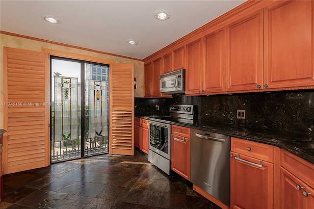 kitchen with stainless steel appliances, dark stone countertops, stone tile flooring, and a healthy amount of sunlight