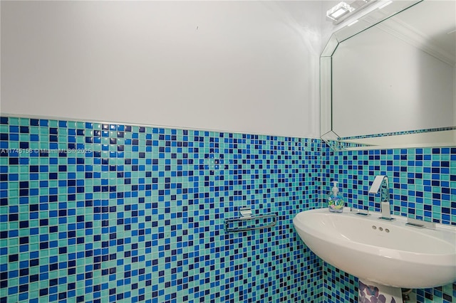 bathroom featuring a wainscoted wall, a sink, tile walls, and crown molding