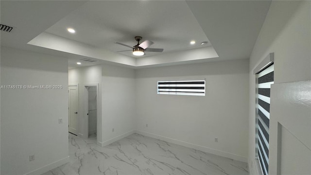 spare room featuring a raised ceiling and ceiling fan