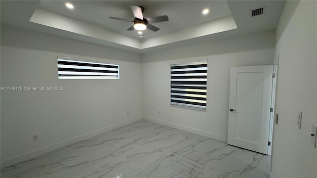 unfurnished room featuring ceiling fan and a raised ceiling