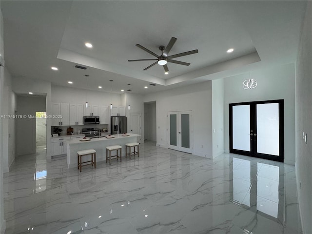 kitchen featuring white cabinetry, stainless steel appliances, an island with sink, and french doors