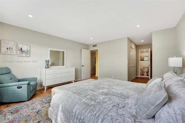 bedroom featuring a closet, ensuite bathroom, and light hardwood / wood-style flooring