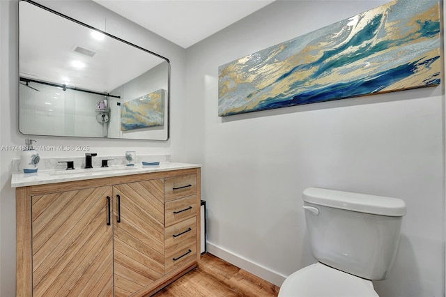 bathroom with hardwood / wood-style flooring, vanity, a shower with shower door, and toilet