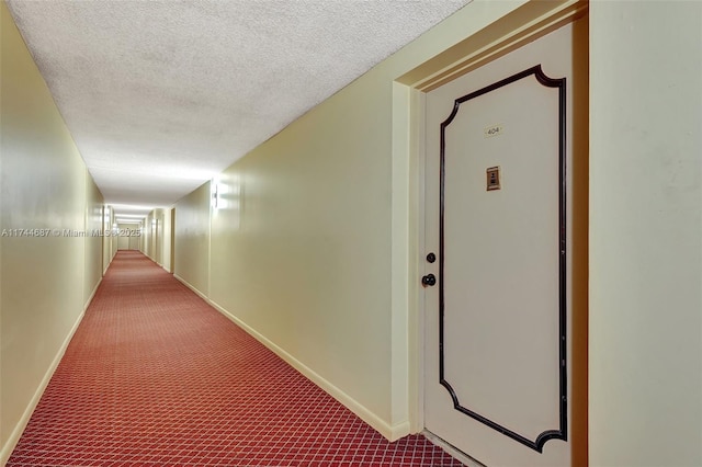 hallway featuring a textured ceiling and dark colored carpet