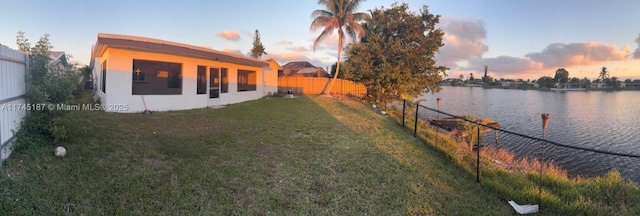 yard at dusk featuring a water view