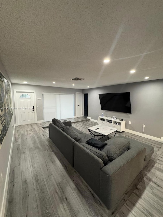 cinema featuring a textured ceiling and light wood-type flooring