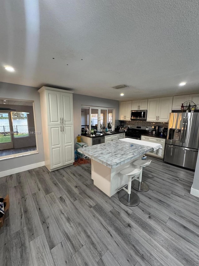 kitchen featuring a kitchen island, white cabinetry, appliances with stainless steel finishes, and light hardwood / wood-style floors