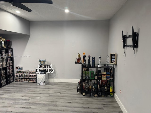 wine area featuring ceiling fan, a textured ceiling, and light wood-type flooring