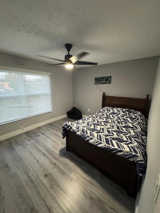 bedroom featuring ceiling fan, a textured ceiling, and light wood-type flooring