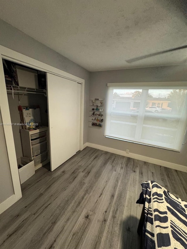 unfurnished bedroom featuring hardwood / wood-style floors, a textured ceiling, and a closet