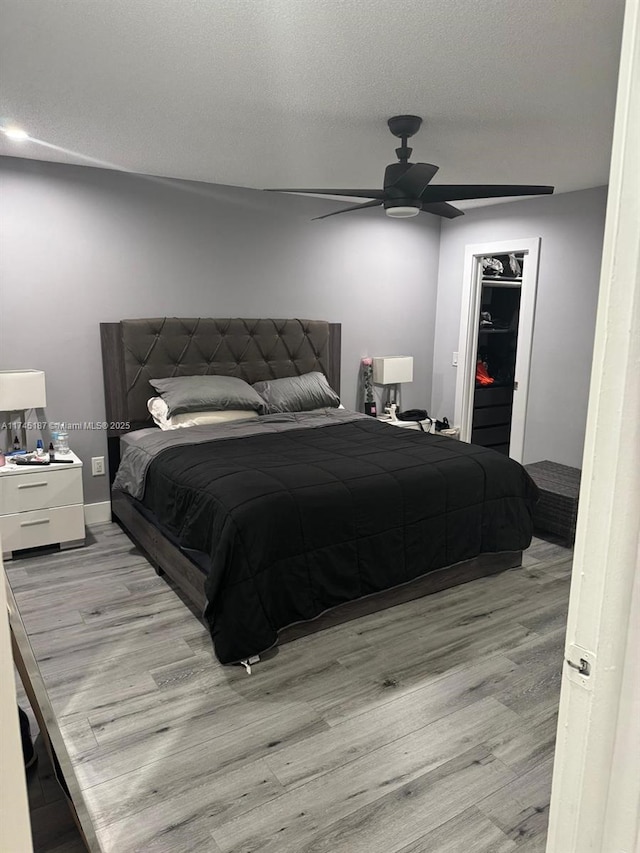 bedroom featuring a closet, a spacious closet, a textured ceiling, and light hardwood / wood-style flooring