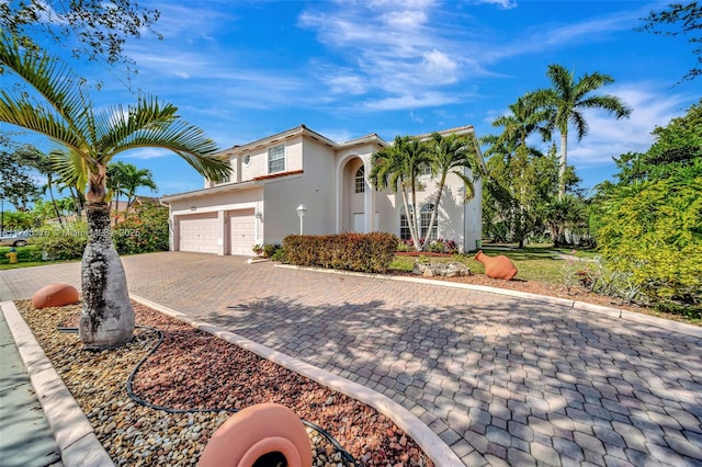 mediterranean / spanish home with stucco siding, decorative driveway, and an attached garage