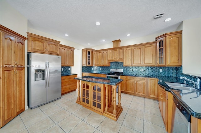 kitchen featuring appliances with stainless steel finishes, dark stone counters, glass insert cabinets, and a sink