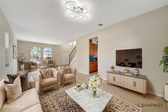 living area featuring light tile patterned floors, visible vents, stairway, and baseboards
