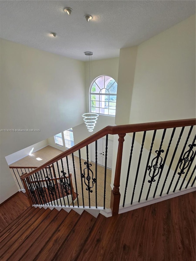 stairway featuring a textured ceiling and wood finished floors