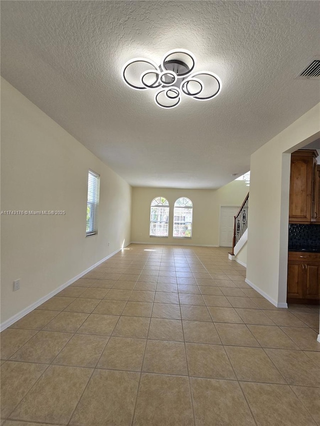 interior space featuring visible vents, stairway, light tile patterned floors, and a textured ceiling