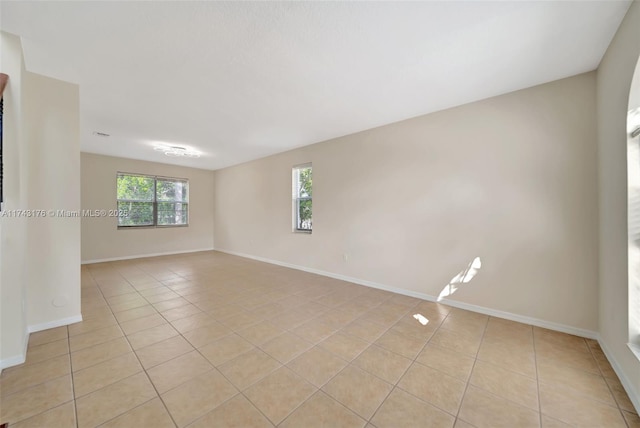 spare room featuring light tile patterned floors and baseboards