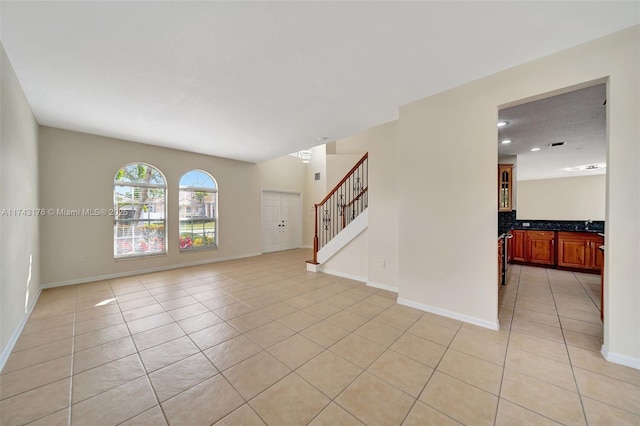 interior space with light tile patterned floors, stairway, and baseboards
