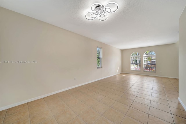 unfurnished room with light tile patterned floors, baseboards, and a textured ceiling