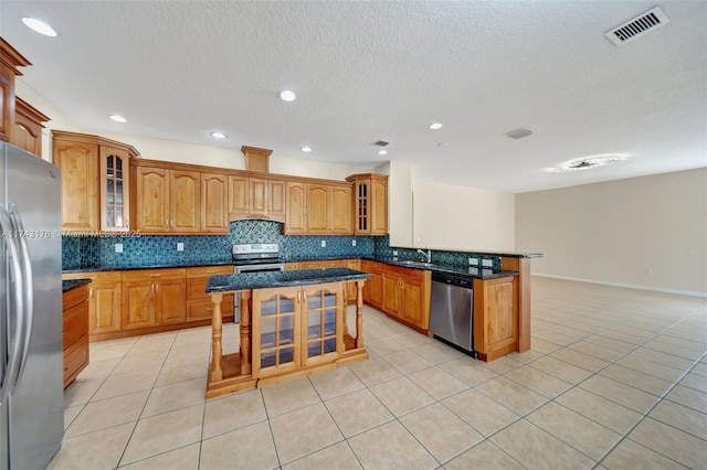 kitchen featuring stainless steel appliances, backsplash, a sink, visible vents, and a peninsula