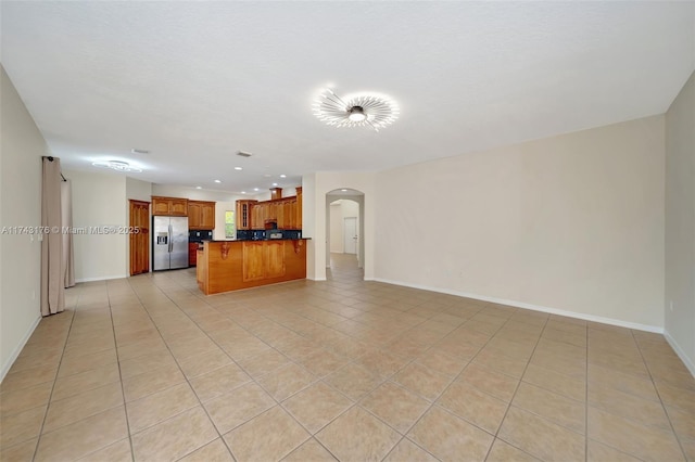 unfurnished living room featuring baseboards, recessed lighting, arched walkways, and light tile patterned flooring
