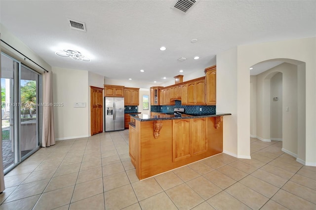 kitchen with visible vents, a peninsula, stainless steel appliances, and plenty of natural light