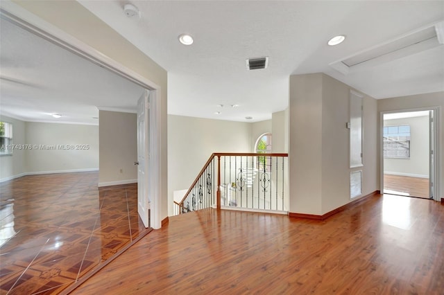 empty room featuring wood finished floors, visible vents, and baseboards