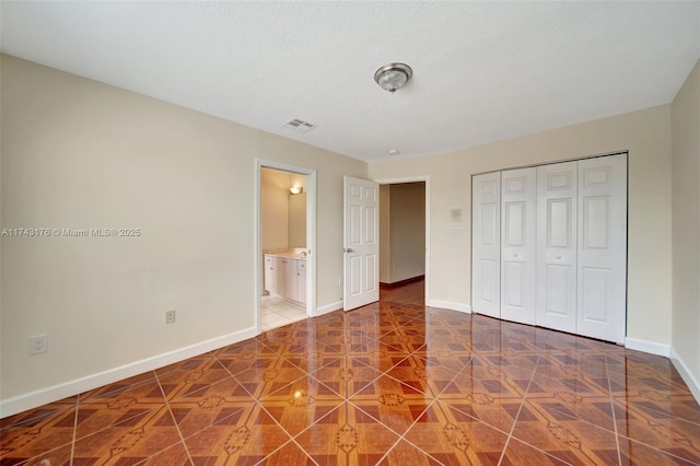 unfurnished bedroom with ensuite bathroom, a closet, visible vents, and baseboards